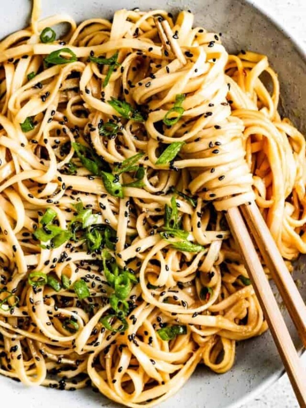 Teriyaki noodles in a bowl sprinkled with green onions and sesame seeds.