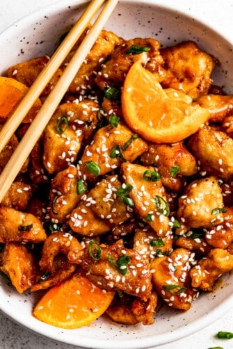 overhead shot of a bowl with mandarin chicken, and chopsticks set on top of the bowl.