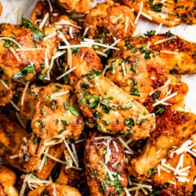 Garlic parmesan chicken wings garnished with parmesan cheese and parsley.