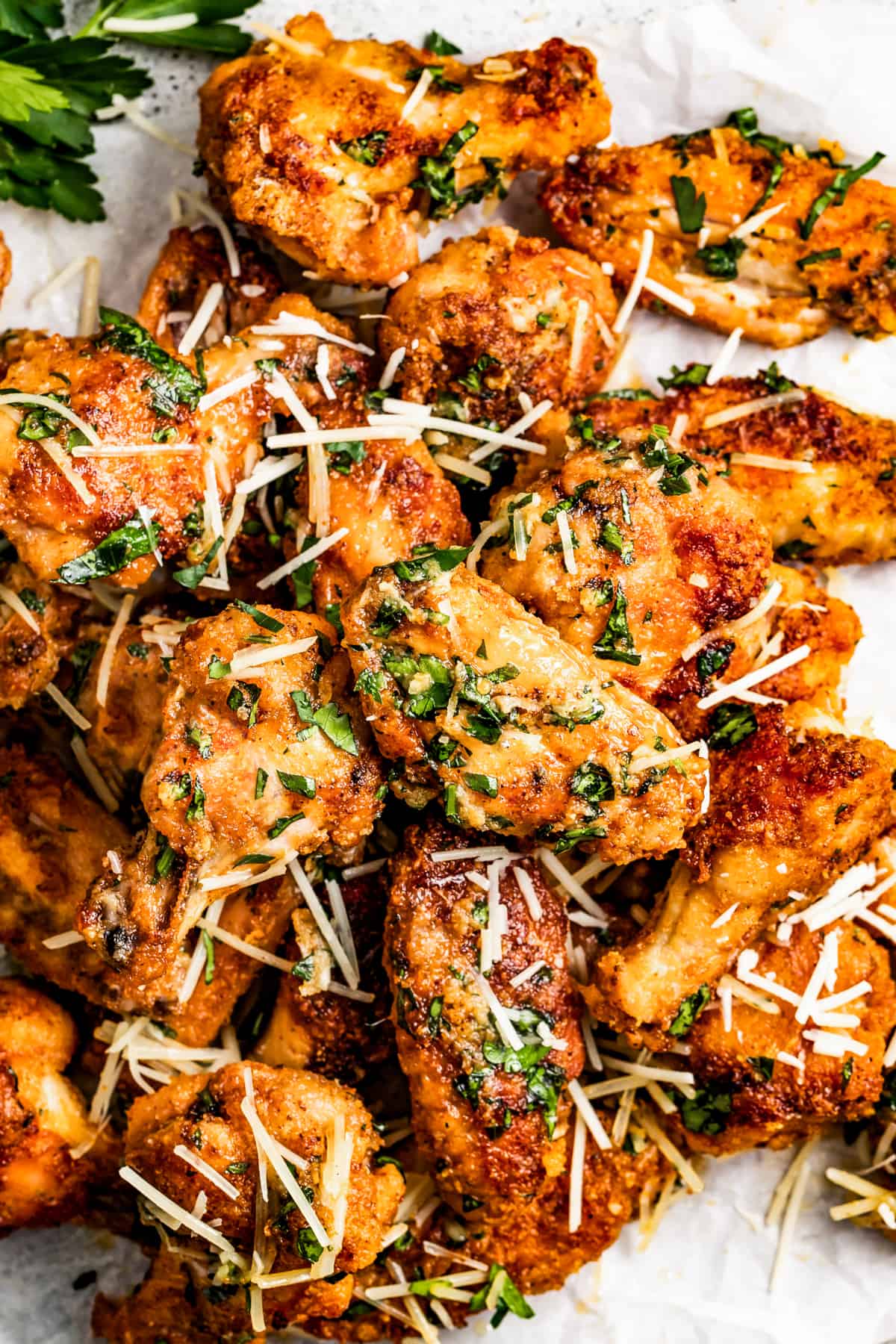 Garlic parmesan chicken wings garnished with parmesan cheese and parsley.