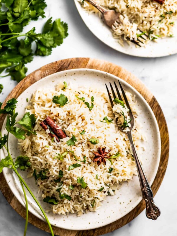 two dinner Plates with cumin rice and a fork placed on the plate.