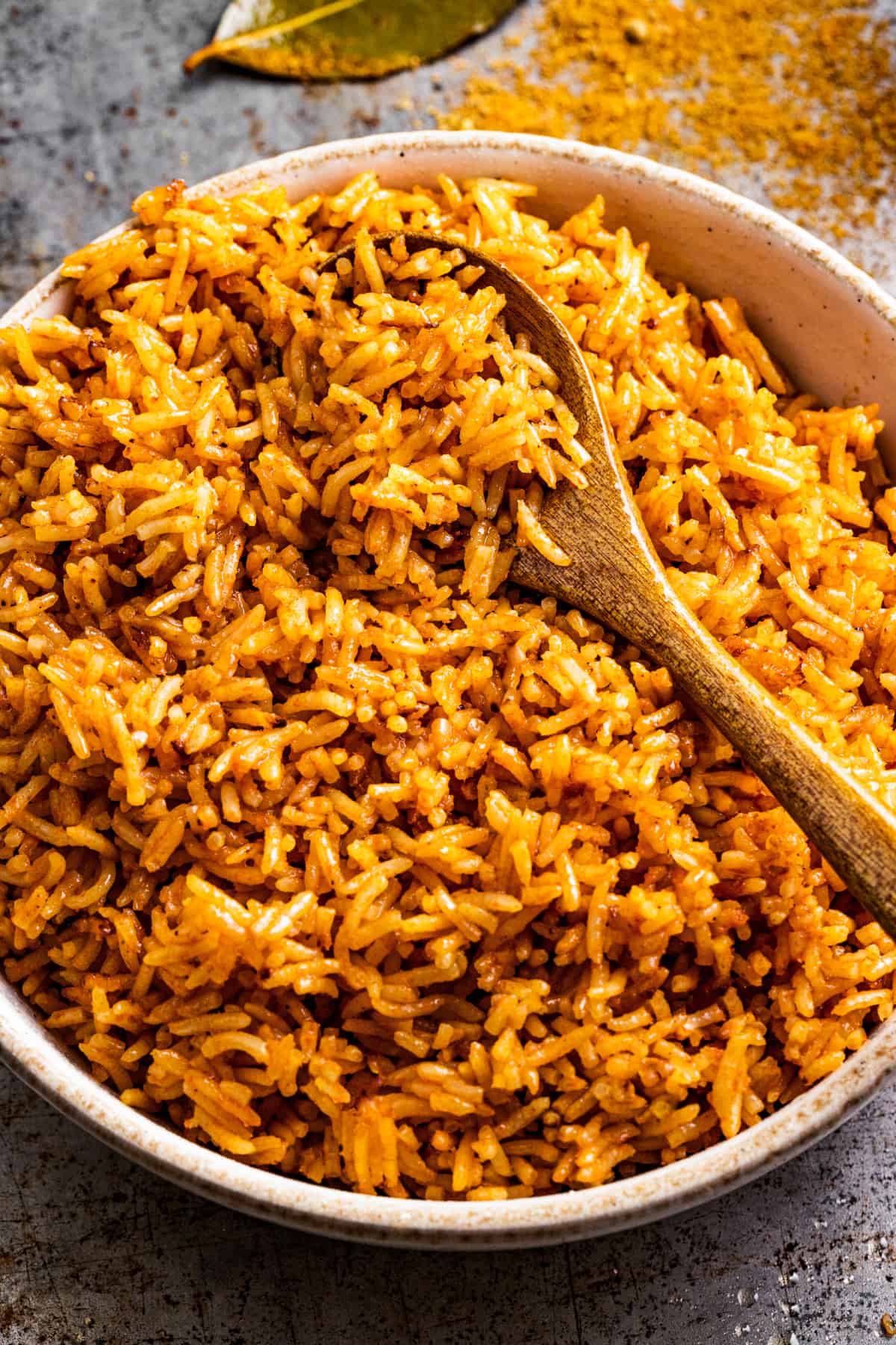 Jollof rice in a serving bowl with a wooden spoon.