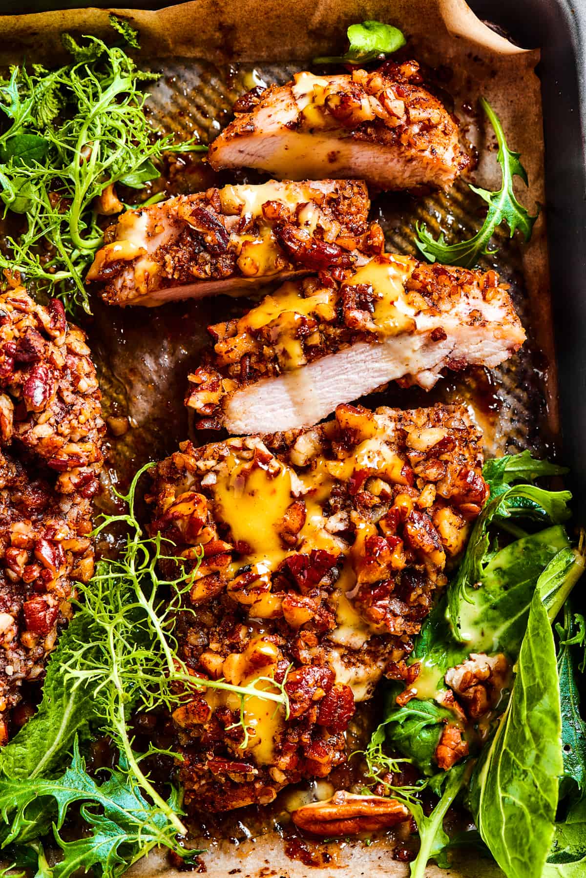 pecan crusted chicken in a tray with green salad placed around it.