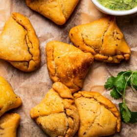 Close-up of homemade samosas with a bowl of chutney placed on the side.