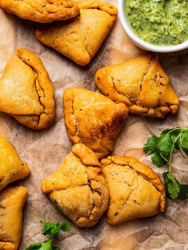 Close-up of homemade samosas with a bowl of chutney placed on the side.