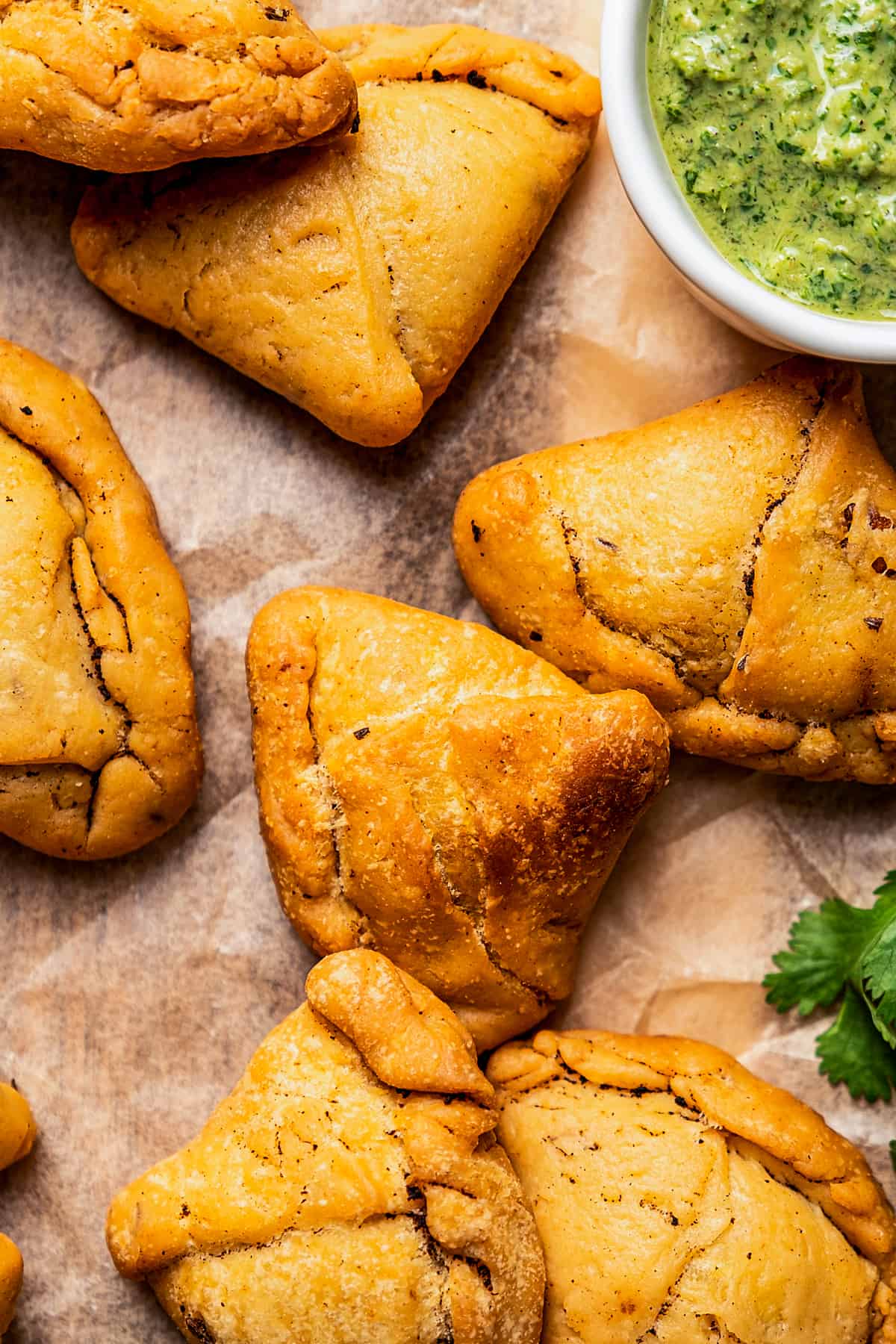 Close-up of homemade samosas with a bowl of chutney placed on the side.
