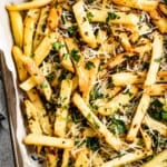 Shot of baked truffle fries garnished with chopped parsley.