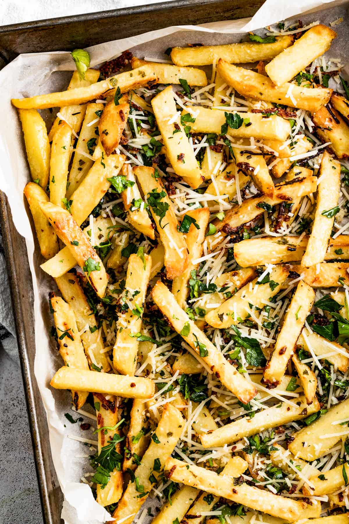 Shot of baked truffle fries garnished with chopped parsley.