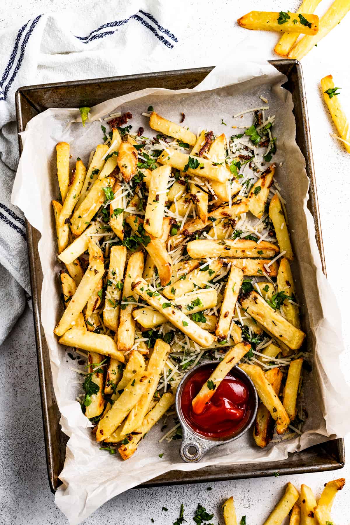 Parmesan truffle fries in a baking pan lined with parchment paper.