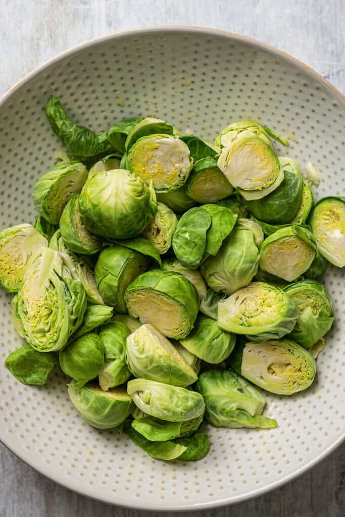 Halved Brussels sprouts in a mixing bowl.