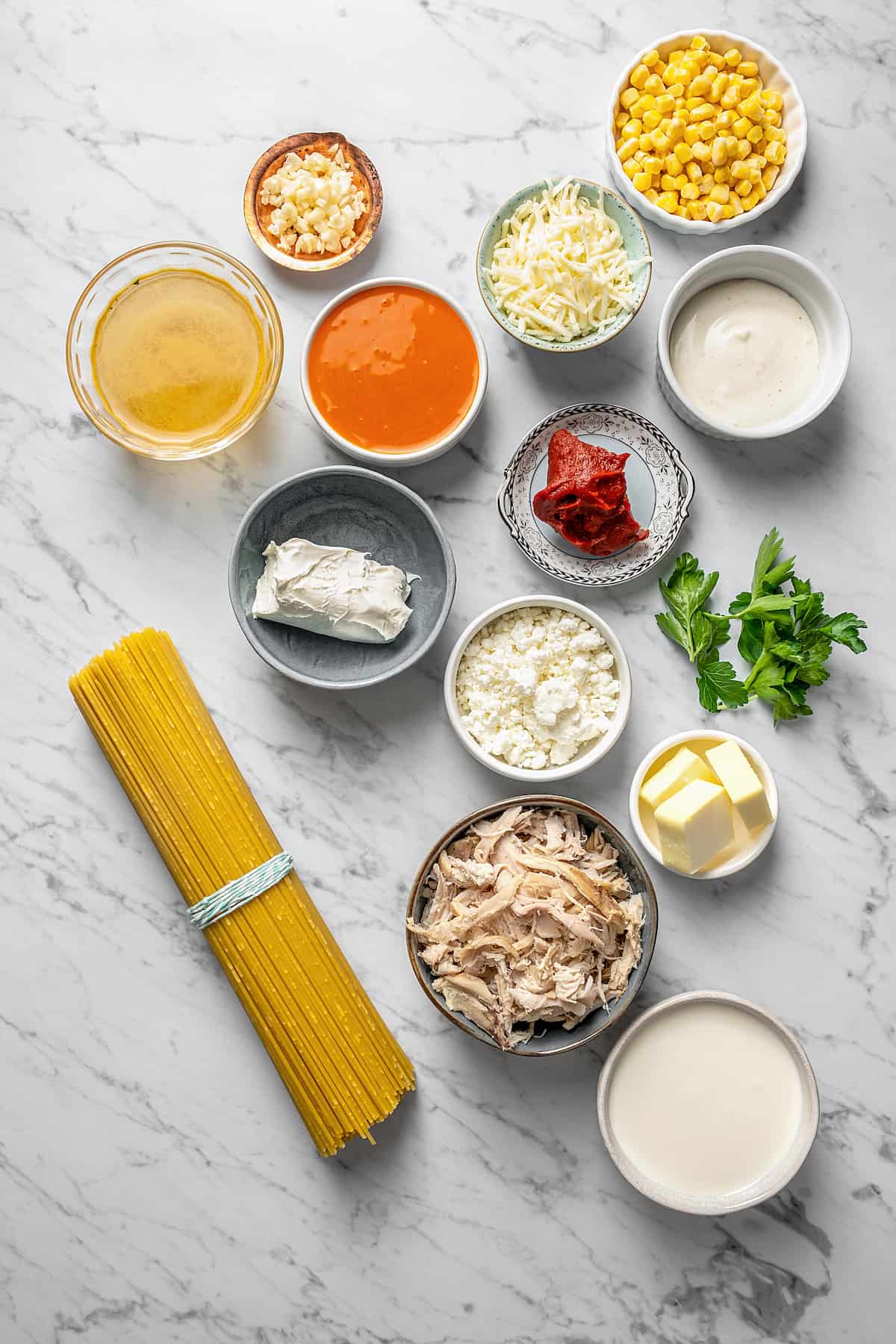 Ingredients for buffalo chicken pasta separated into bowls.