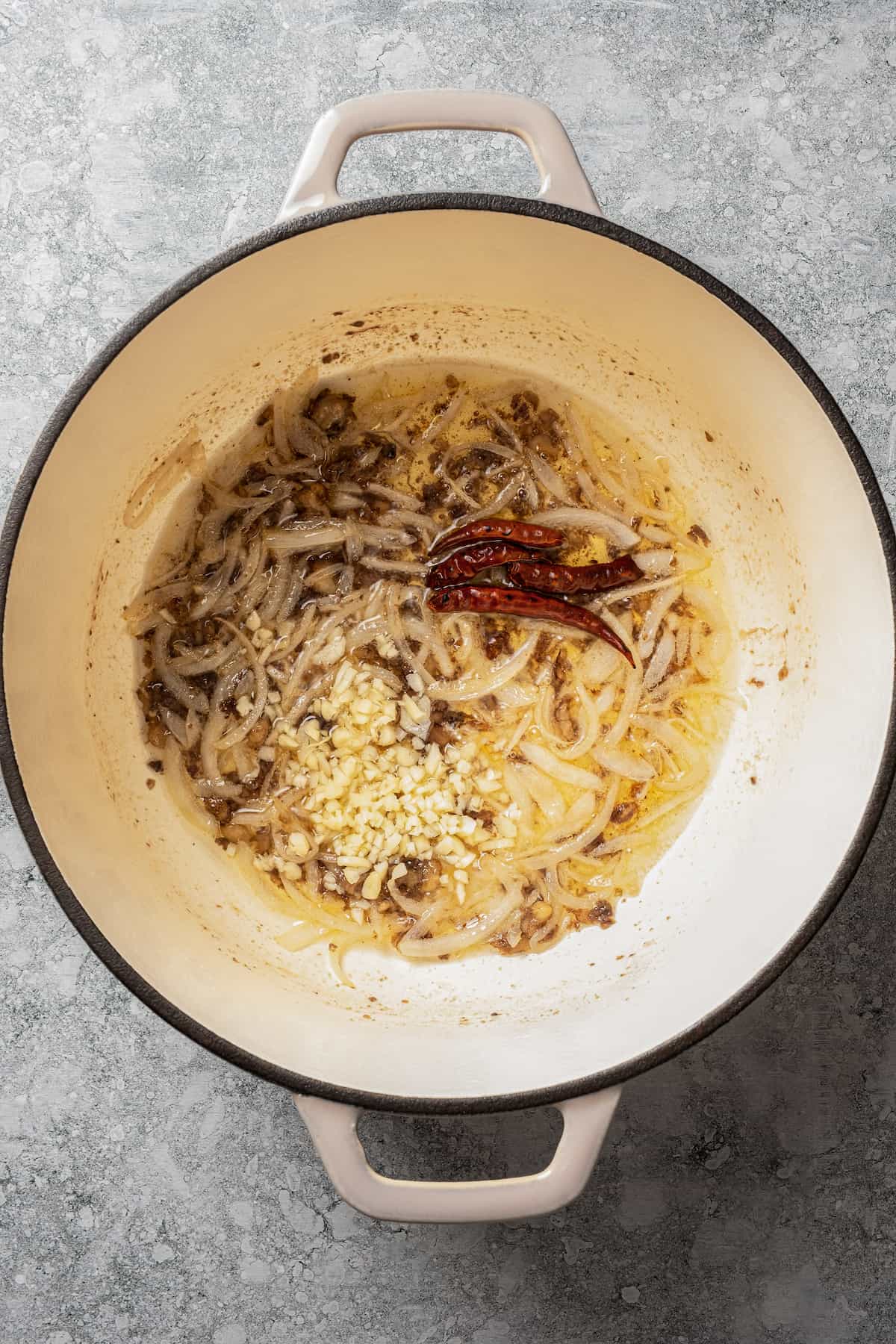 Cooking garlic and chile de arbol in a pot with onions.
