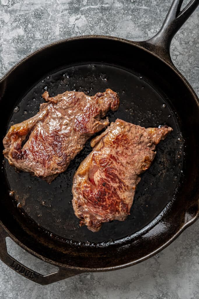 Seared ribeye steaks in a skillet.