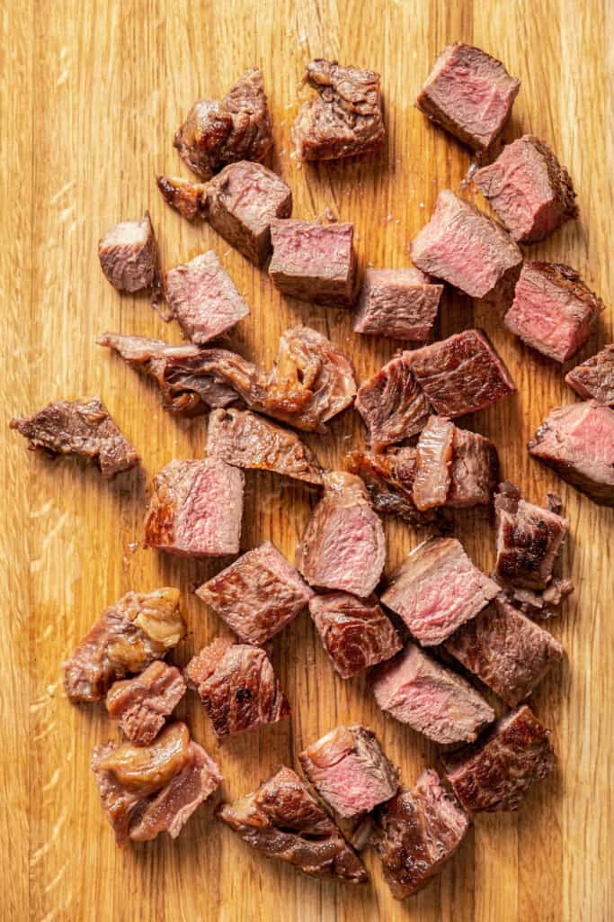 Cubed ribeye steak on a cutting board.