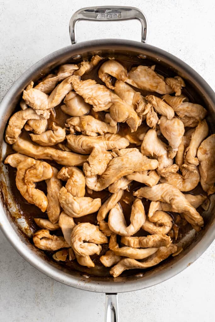 Browning thinly sliced chicken in a pan.