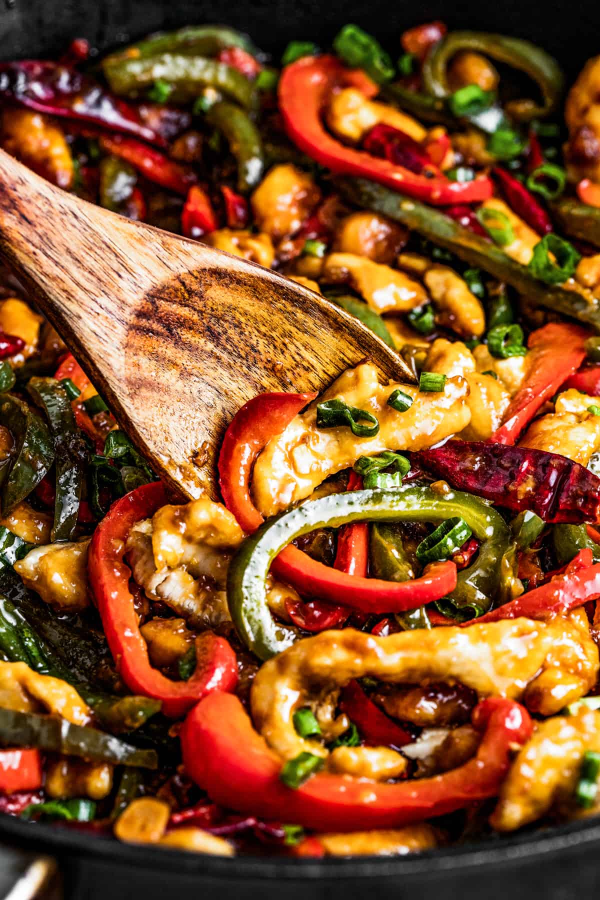 Stirring Szechuan chicken with a wooden spoon.