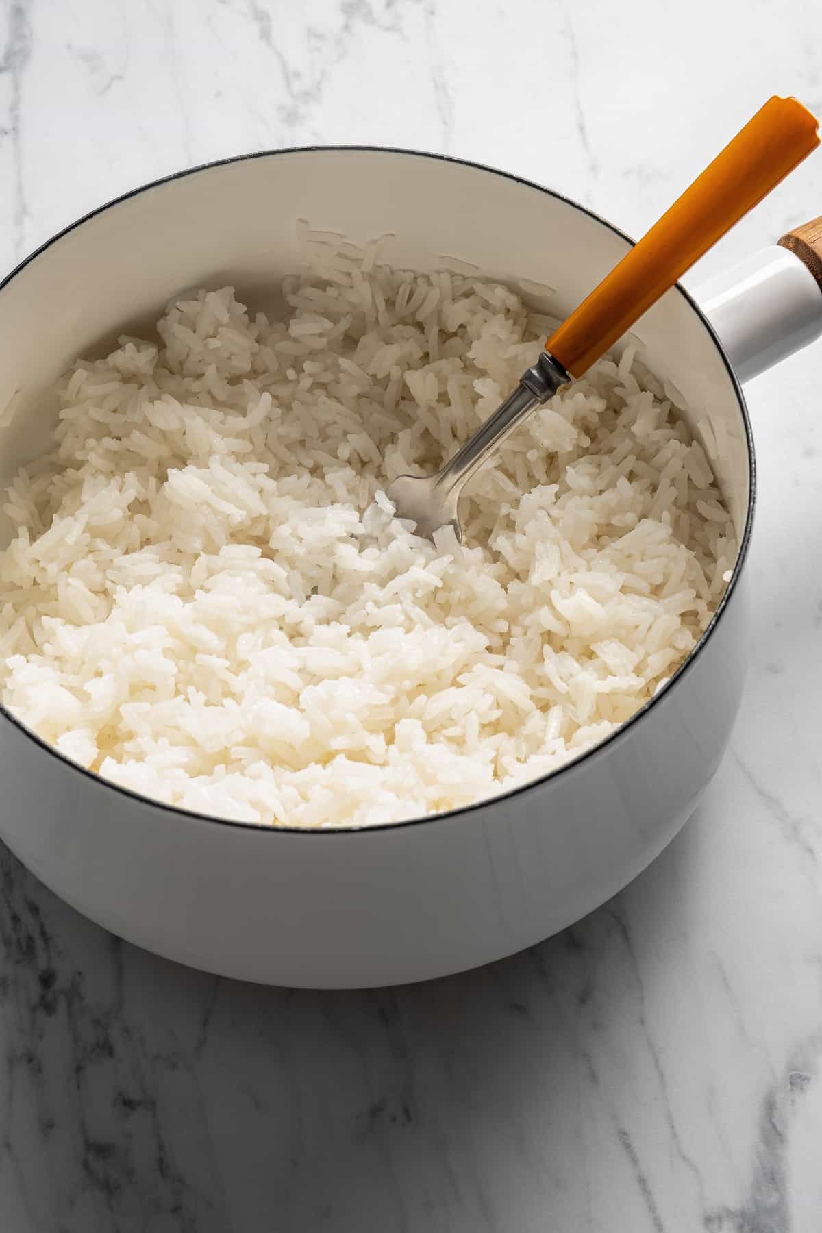 Fluffing cooked wite rice with a fork.