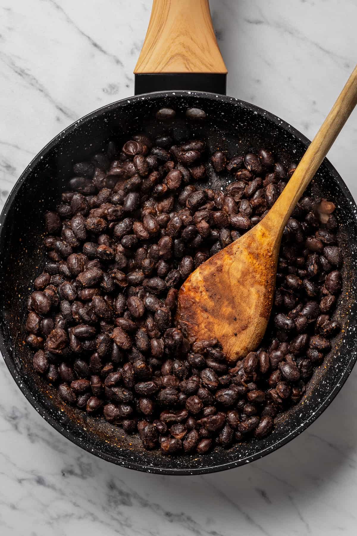 Cooking black beans in a skillet.