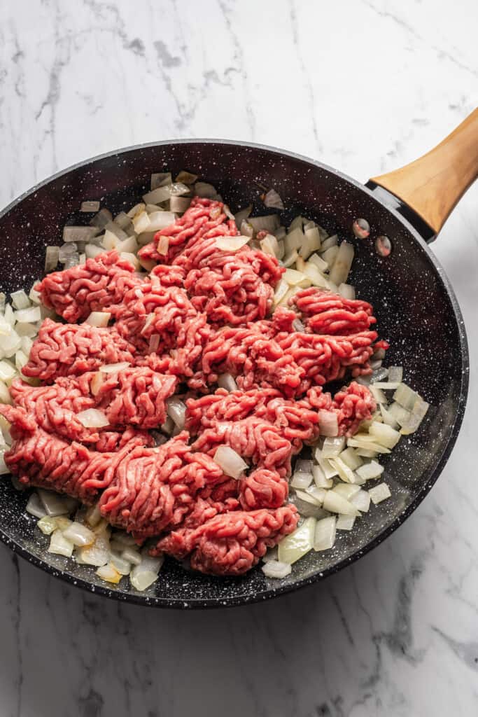 Browning seasoned beef with onions in a skillet.