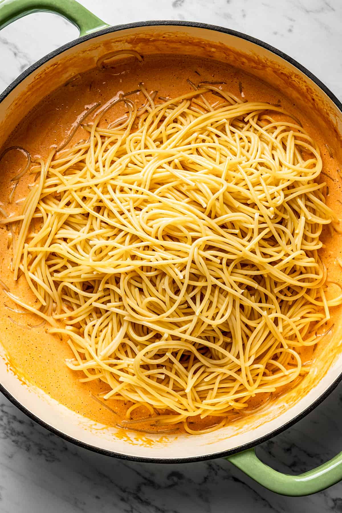 Adding spaghetti to buffalo pasta sauce.