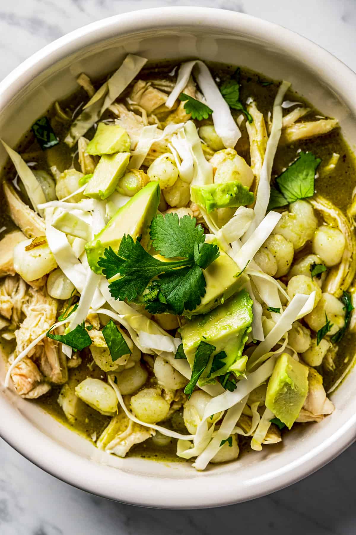 Pozole verde in a bowl with garnishes.