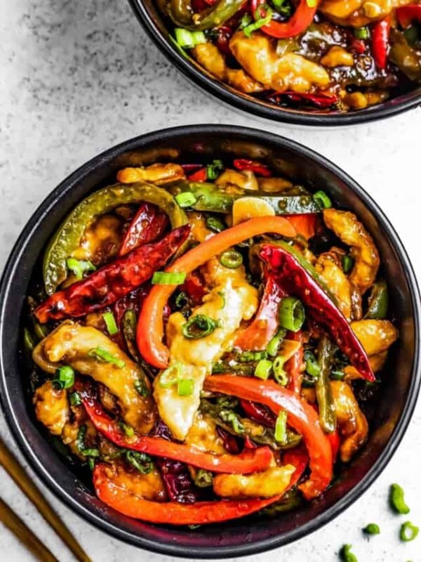 Szechuan chicken served in bowls near chopsticks.