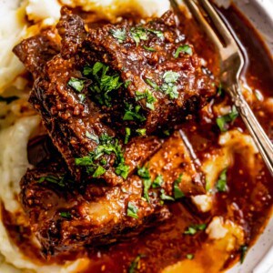 Overhead shot of a bowl with Instant pot short ribs served over mashed potatoes and garnished with parsley.