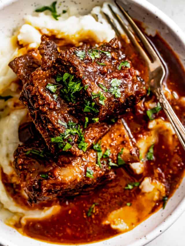 Overhead shot of a bowl with Instant pot short ribs served over mashed potatoes and garnished with parsley.