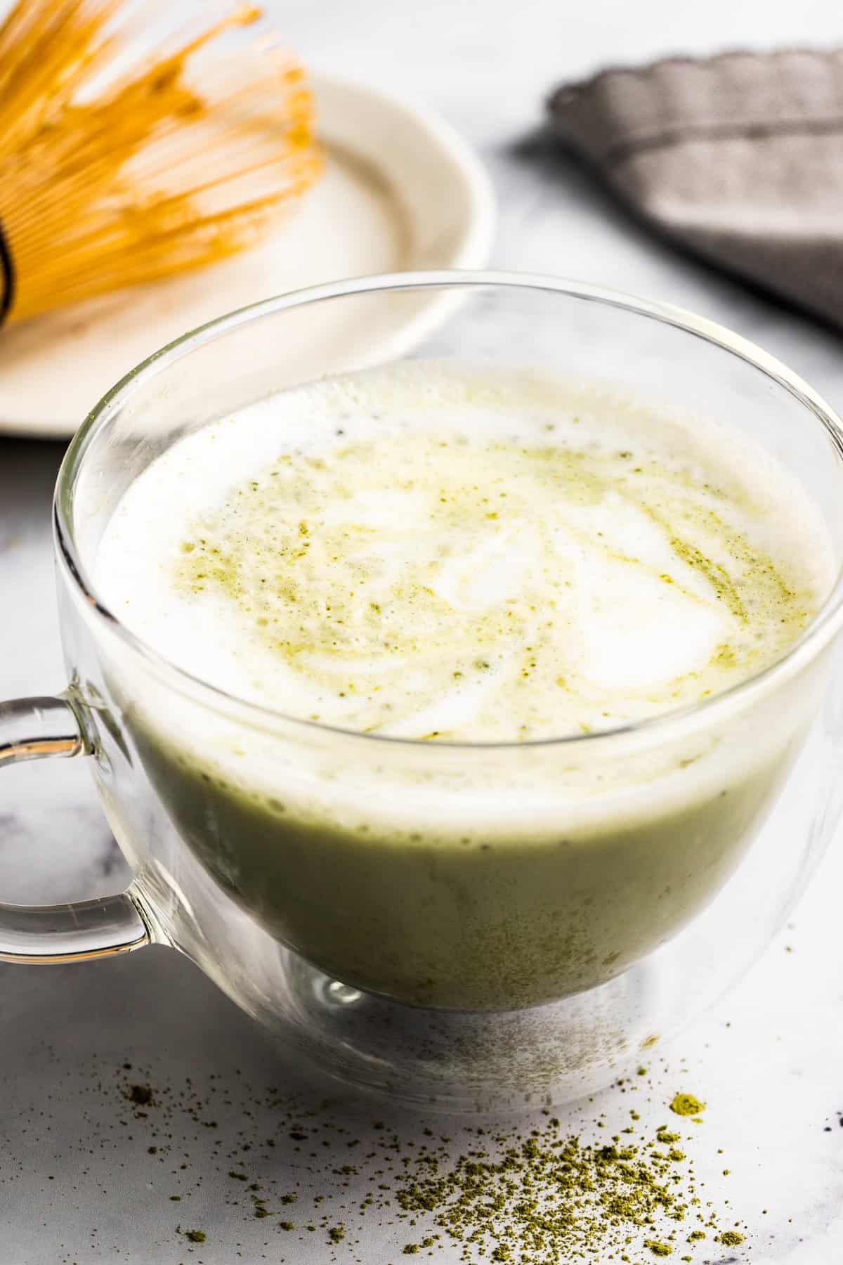 Warm matcha latte in a clear glass mug.