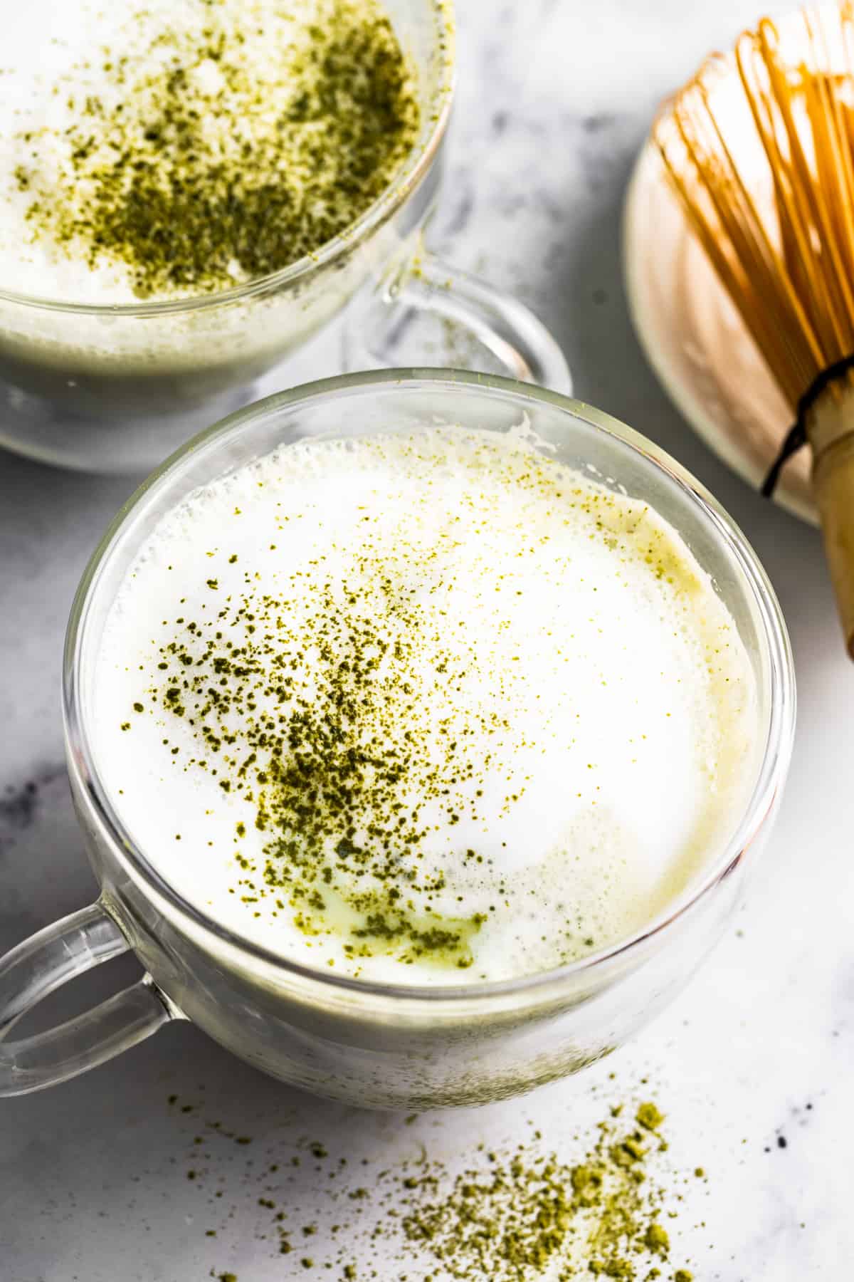 Overhead of matcha latte with frothy milk and a sprinkle of matcha on top.