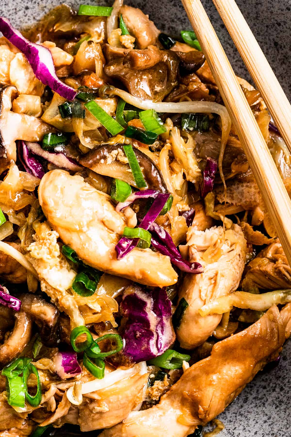 Closeup of moo shu chicken, with chopsticks set to the right of them.