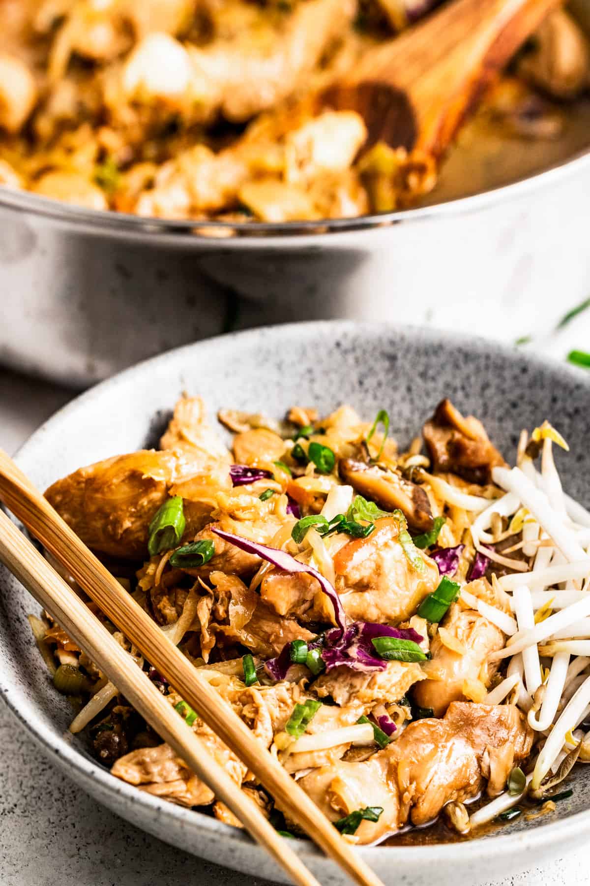moo shu chicken served in a bowl, with a skillet of moo shu chicken placed right behind the bowl.
