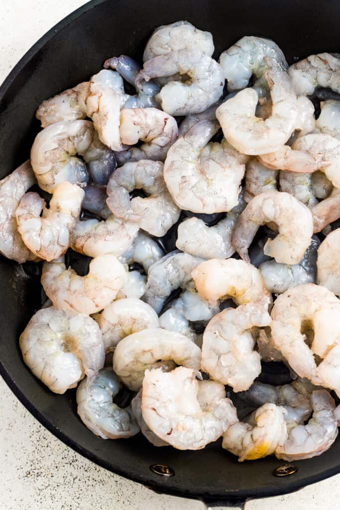 Cooking raw shrimp in a skillet.