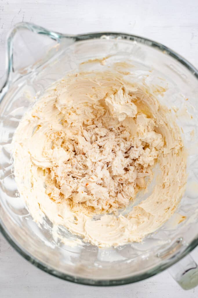 Adding crab meat to a cream cheese mixture.