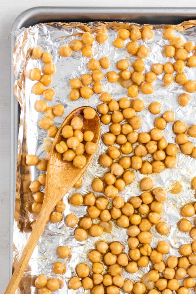 Seasoned chickpeas on a baking sheet lined with aluminum foil ready to be toasted.