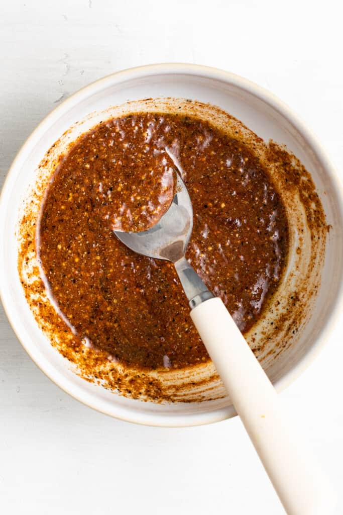 Mixing together a rub for Peruvian chicken in a bowl with a spoon.