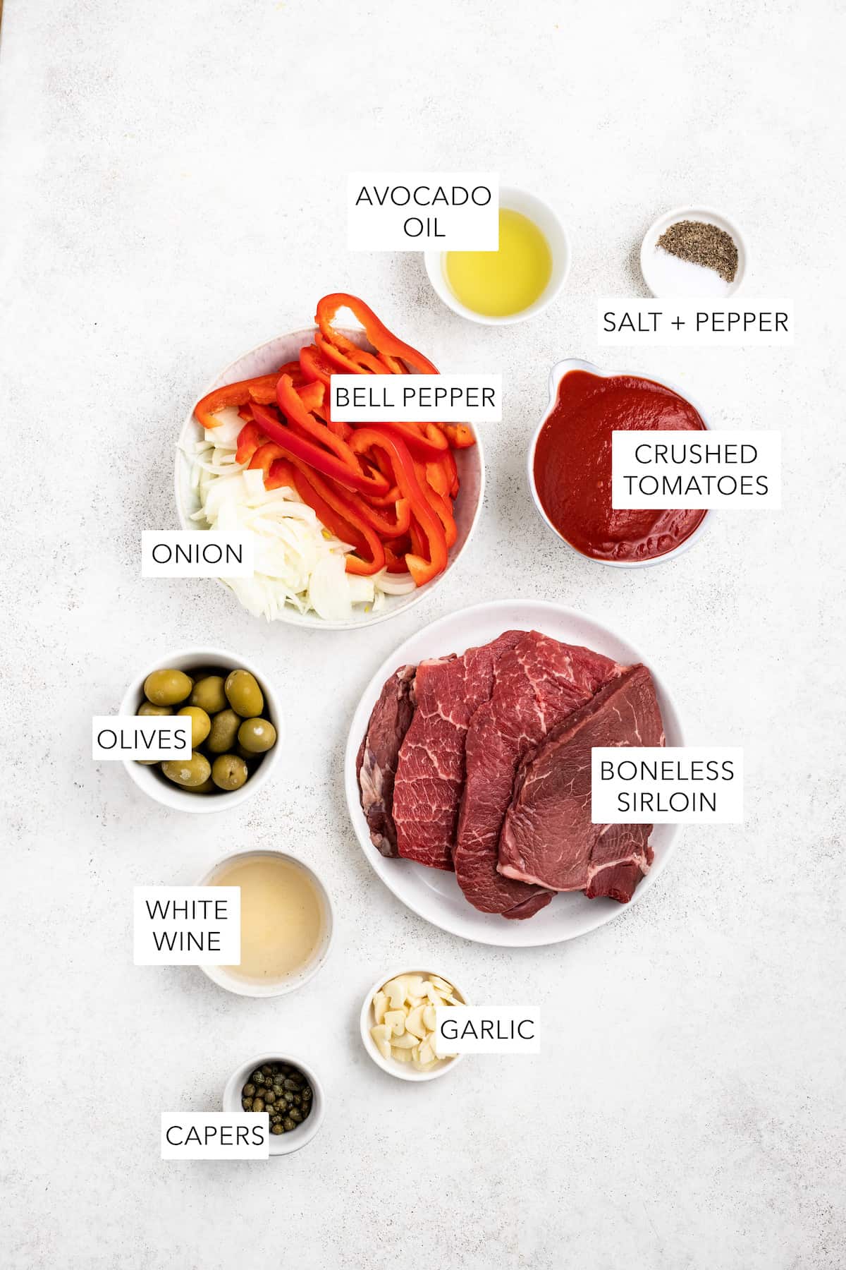 Ingredients for steak pizzaiola separted into bowls and labeled.