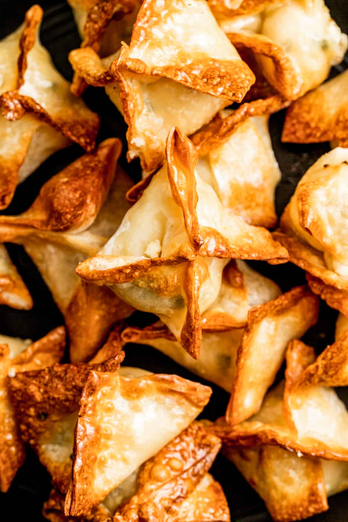 Closeup of crab rangoon piled on top of each other.