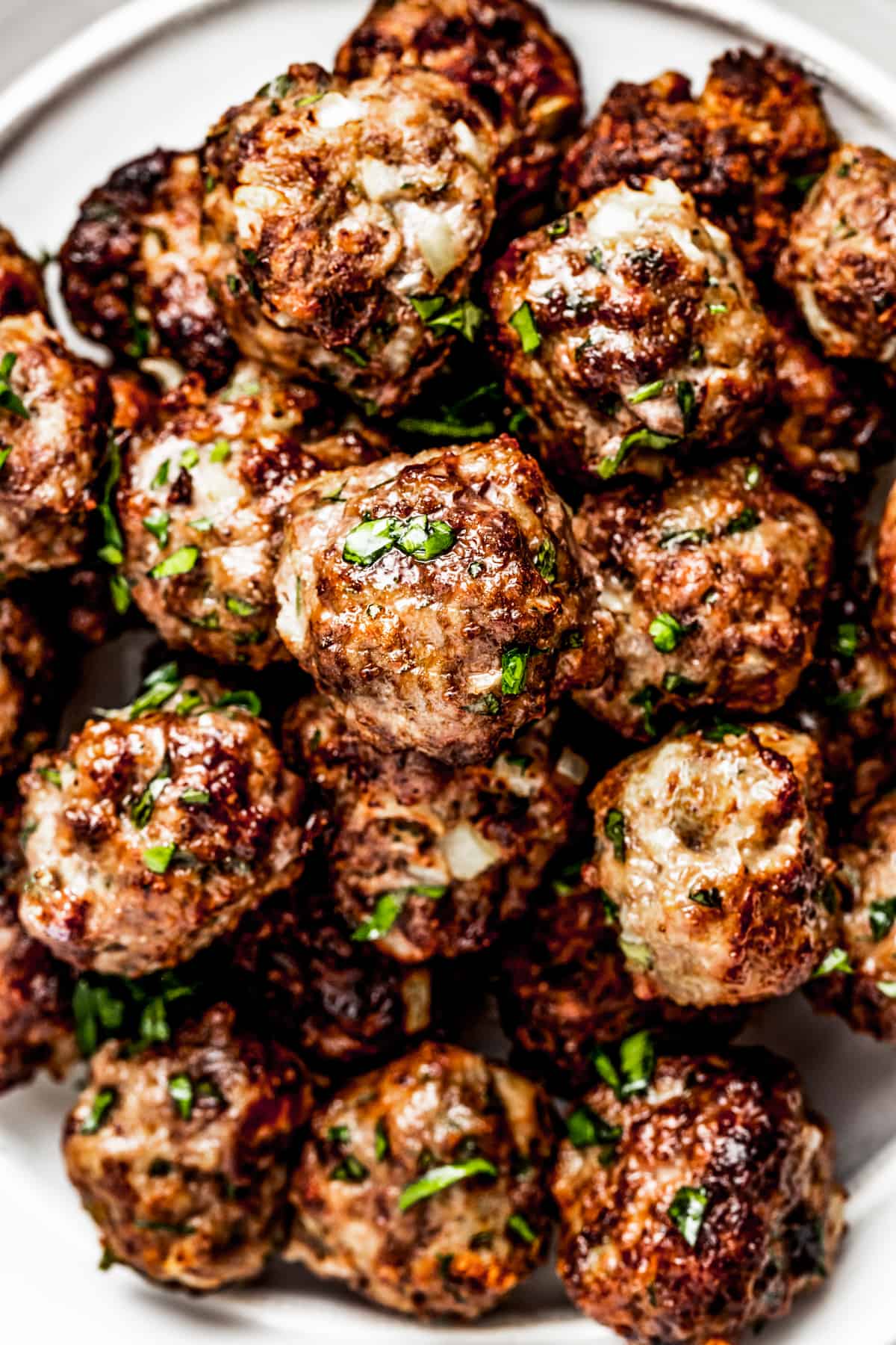 Overhead shot of a pile of air fryer meatballs served on a white serving plate.