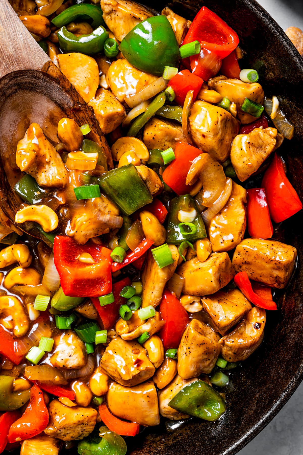 Close-up image of cashew chicken cooking in a dark skillet.