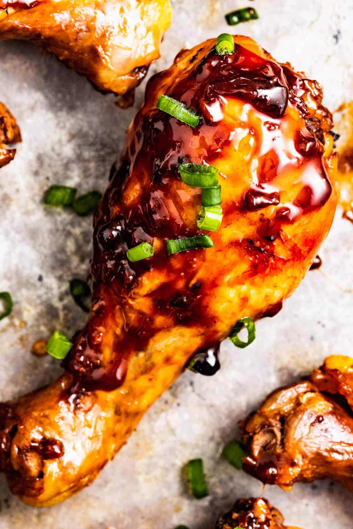 Closeup of broiled chicken adobo drumsticks on a sheet pan.