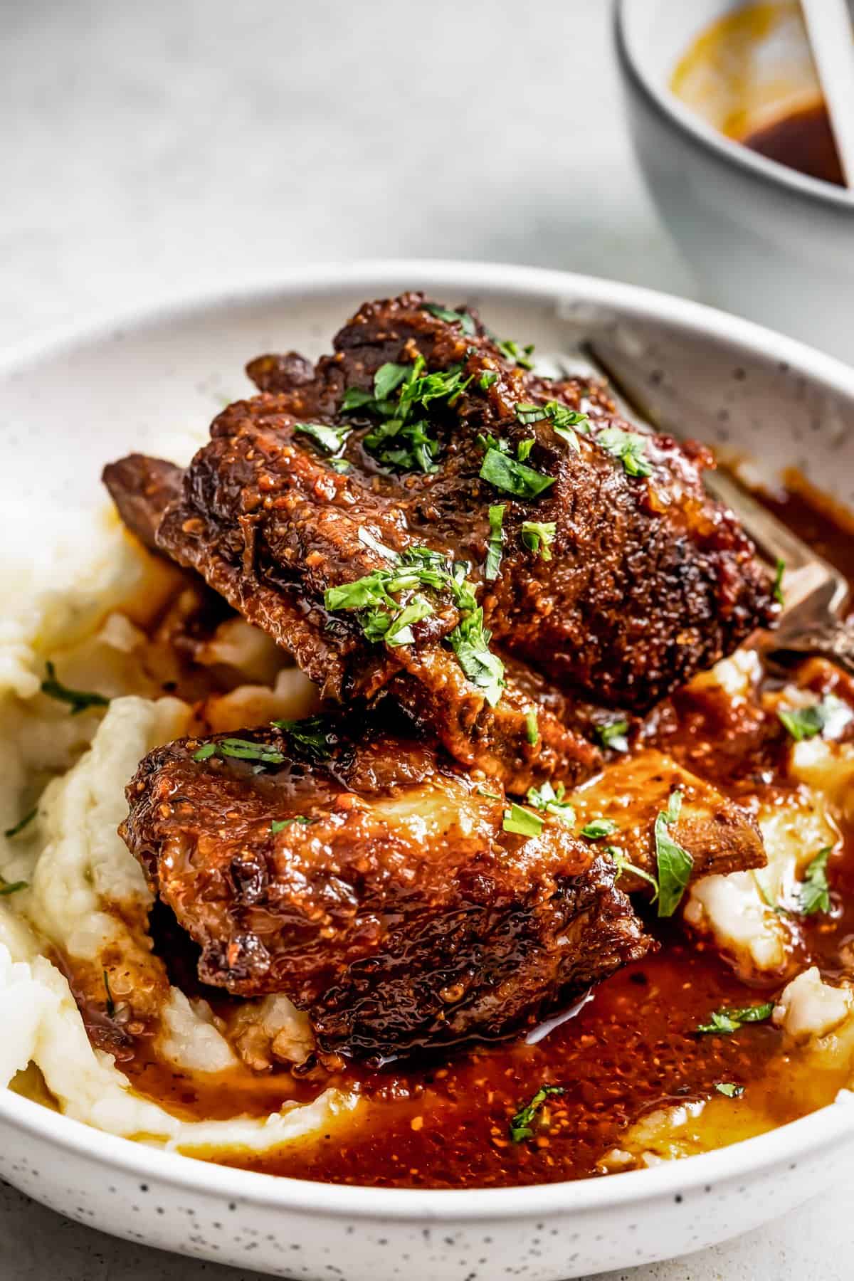 Instant pot short ribs served over mashed potatoes and garnished with parsley.