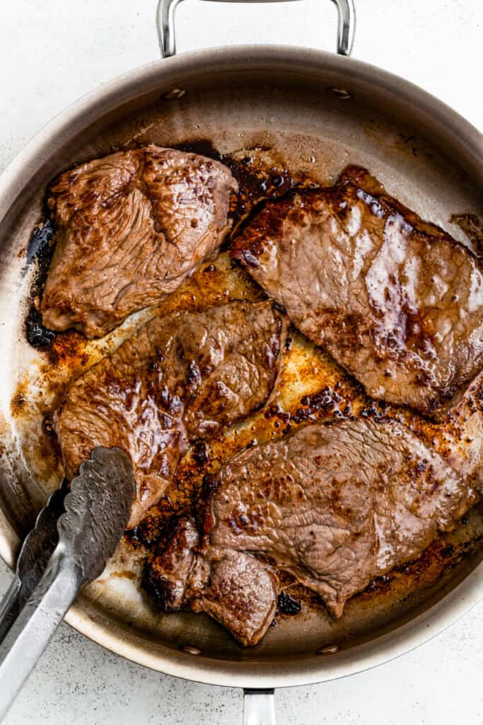 Searing four steaks in a pan.