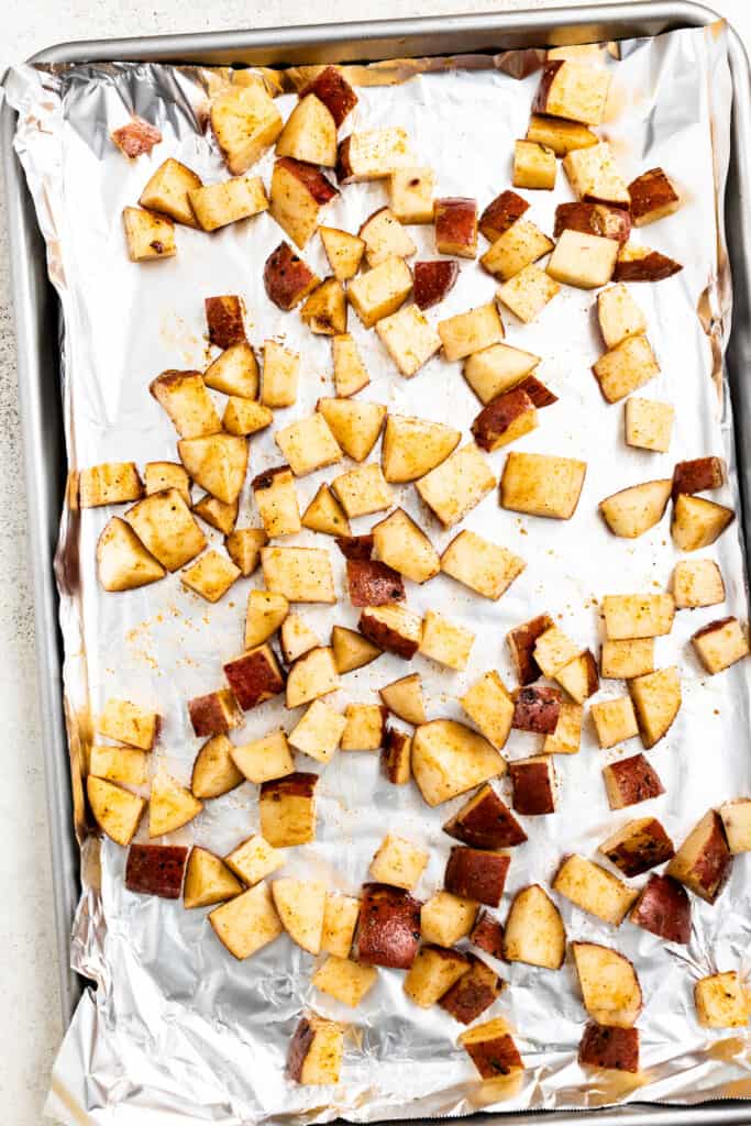 Cubed potatoes arranged on a baking sheet lined with aluminum foil ready to be roasted.