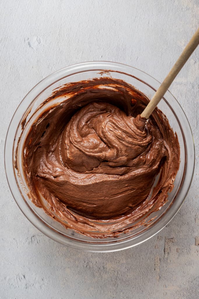 Folding chocolate mixture into whipped cream to make chocolate mousse.