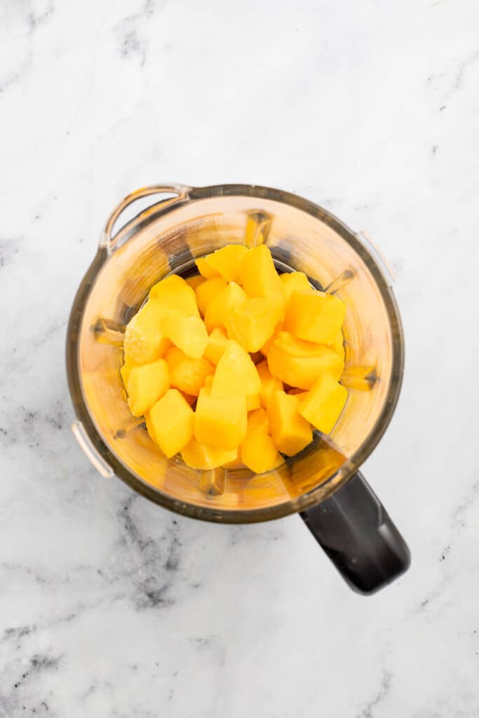 Adding mangos to a blender.
