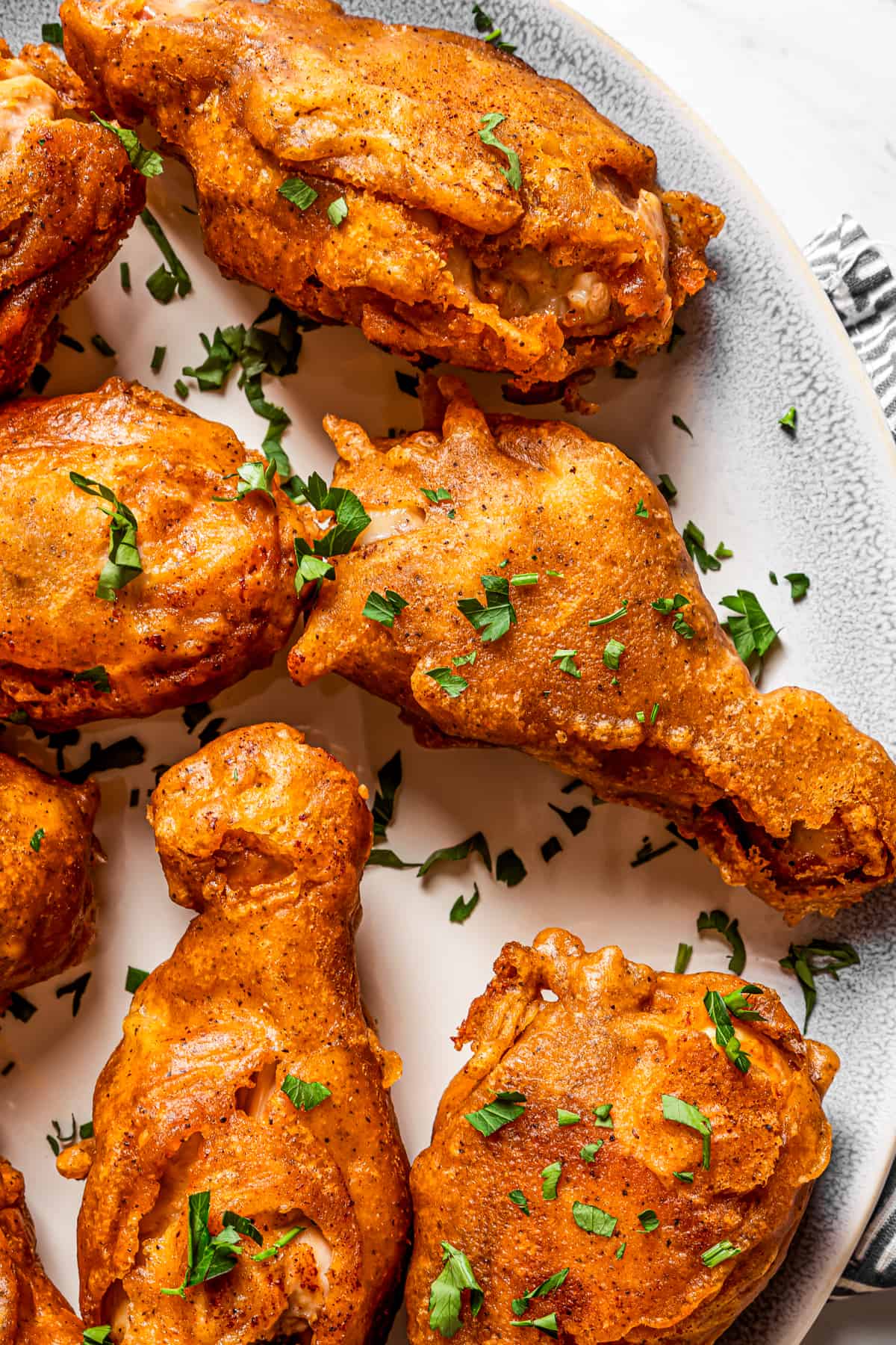 Close-up shot of beer-battered chicken drumsticks arranged on a serving plate.