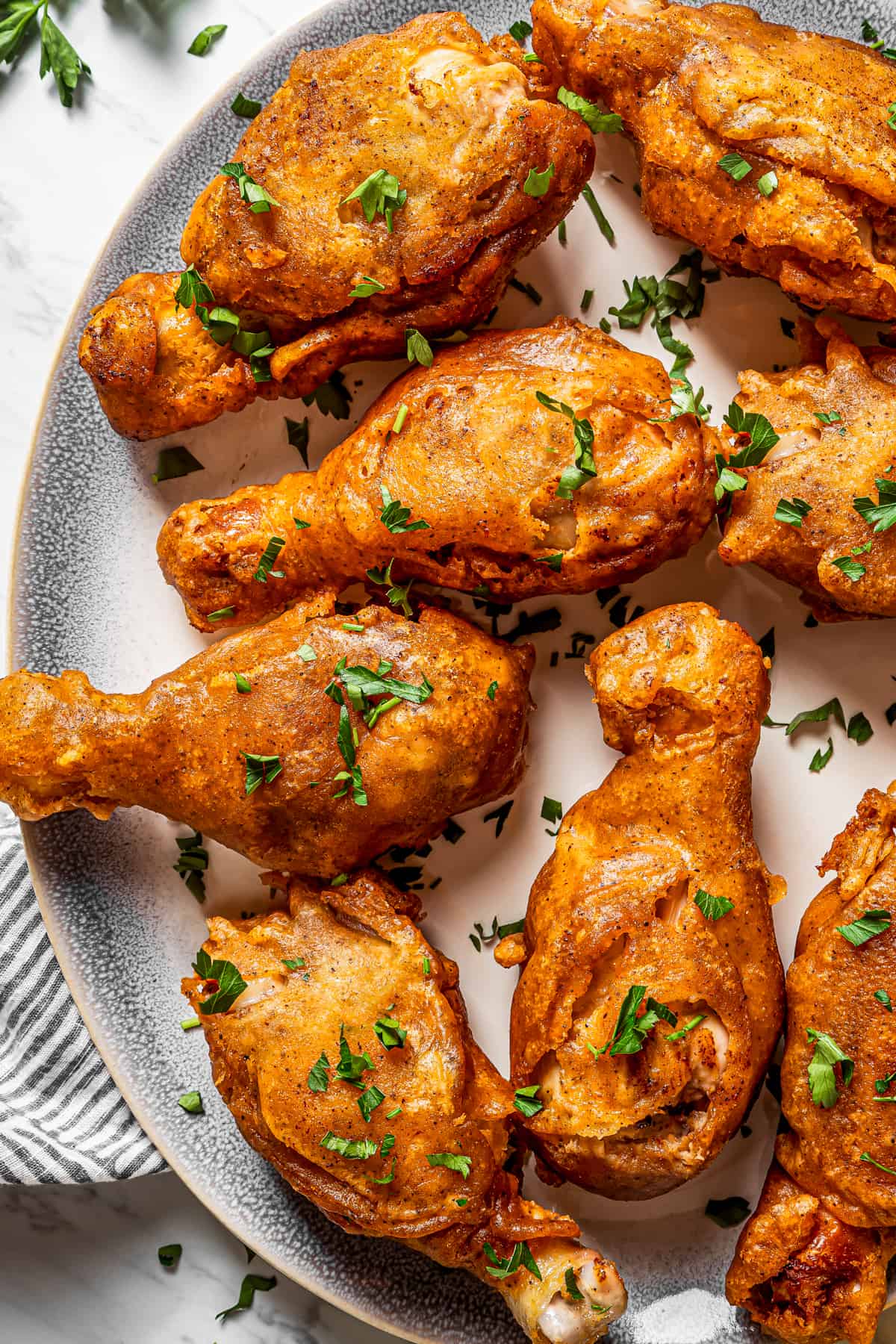 Close-up shot of beer-battered chicken drumsticks arranged on a serving plate.