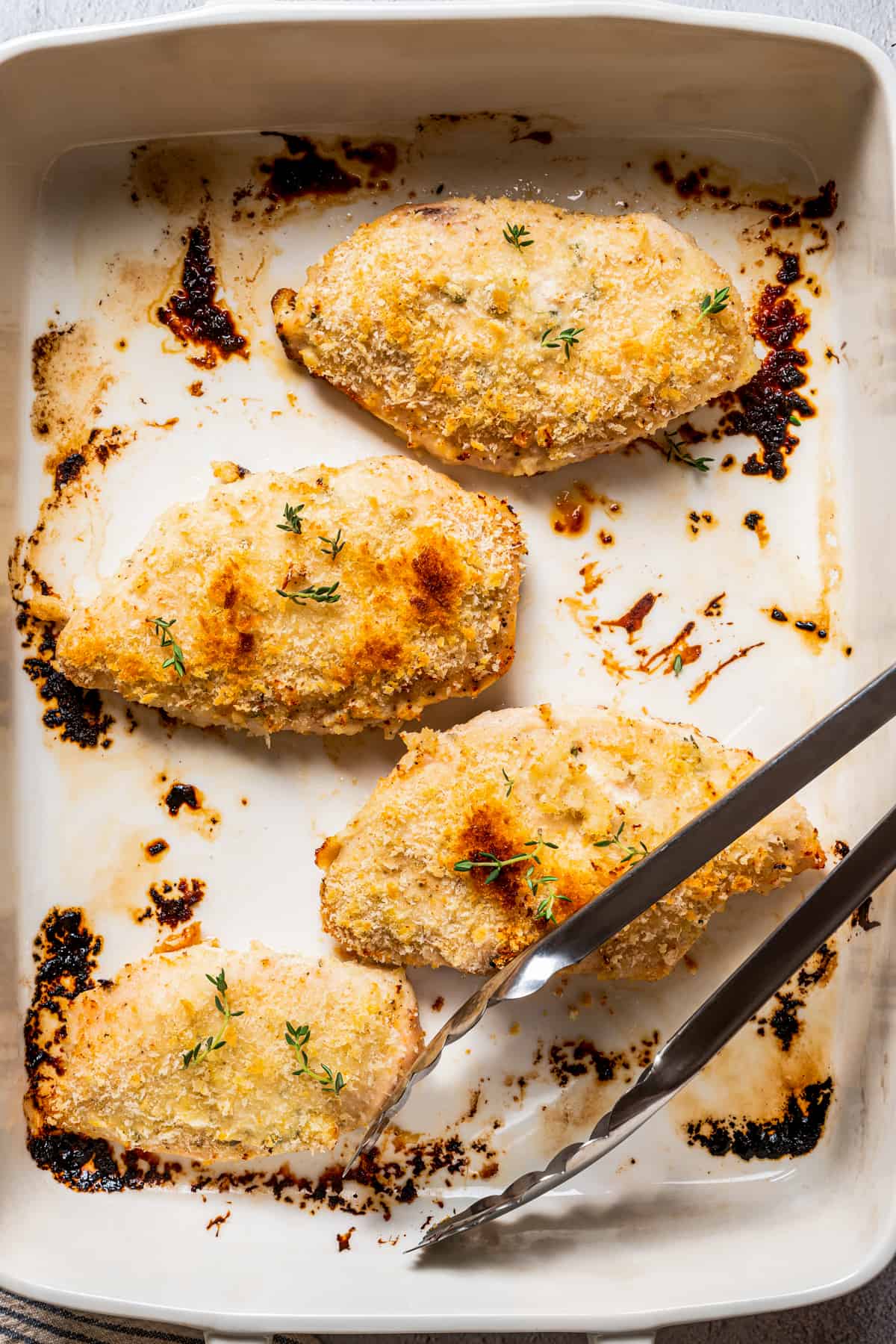 Cooked Yogurt Marinated chicken on a baking sheet with tongs