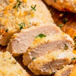 Close up of baked chicken breasts sliced on a cutting board.